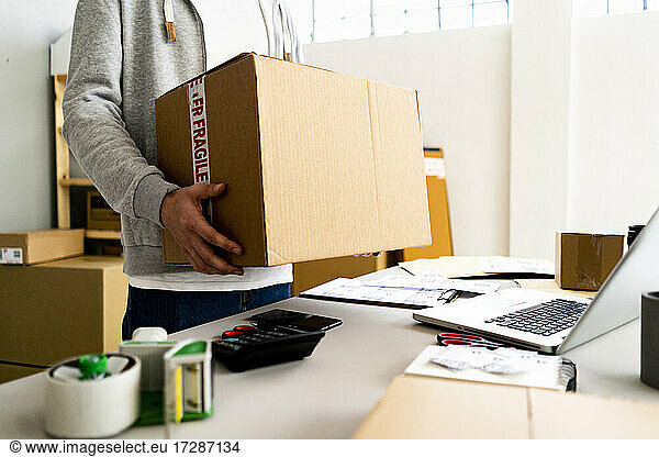 Businessman carrying cardboard box at desk