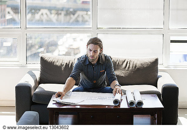 Businessman checking blueprint on table in creative office