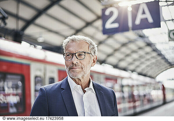 Businessman contemplating while standing at railroad station