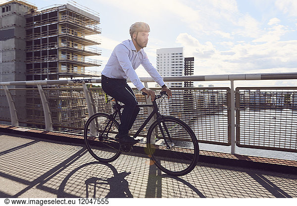 Businessman cycling on footbridge against sky