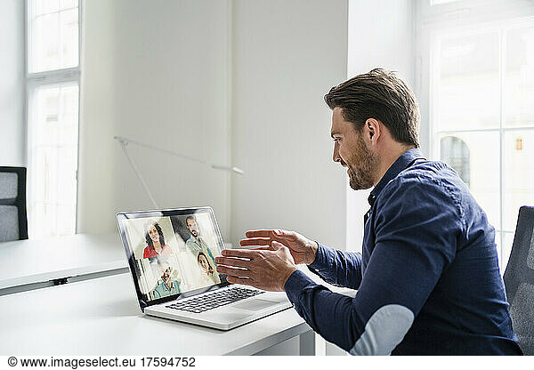 Businessman discussing ideas with colleagues on video call through laptop at office