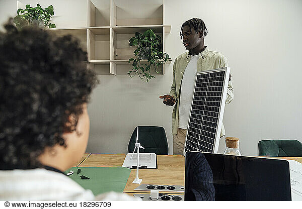 Businessman discussing over solar panel with colleague in office