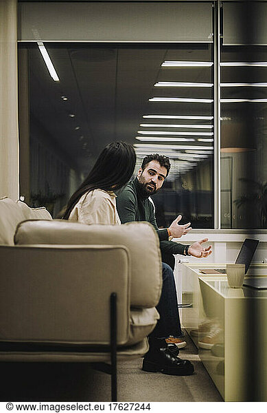 Businessman discussing strategy with female colleague while working late at work place