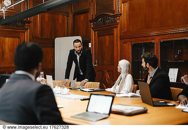 Businessman discussing with colleagues in board room during conference meeting