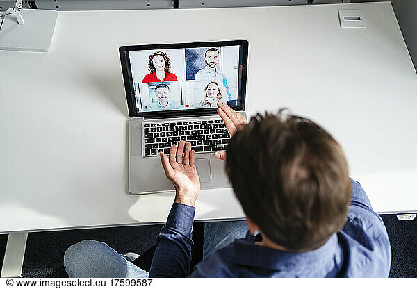 Businessman discussing with colleagues in web conference meeting on laptop at office