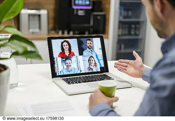 Businessman discussing with colleagues on video call at home office
