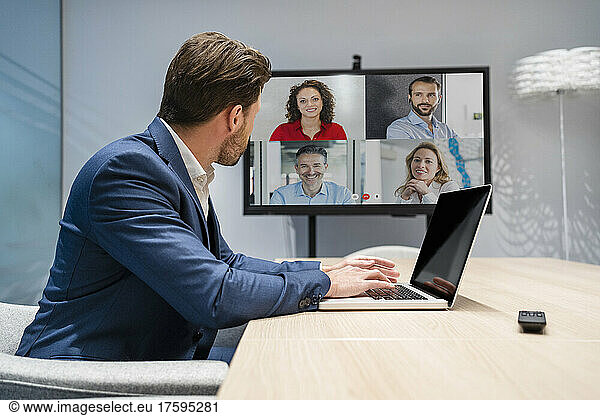 Businessman discussing with colleagues on video call in board room