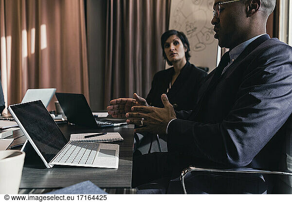 Businessman discussing with female colleague in board room during meeting
