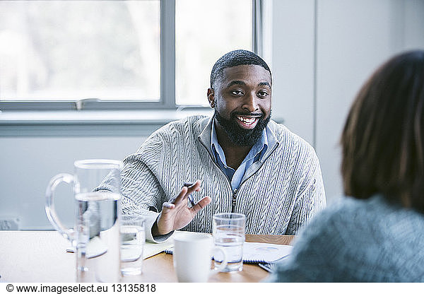 Businessman discussing with female colleague in meeting at board room