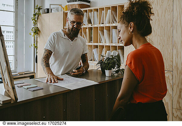 Businessman discussing with female colleague over document in office