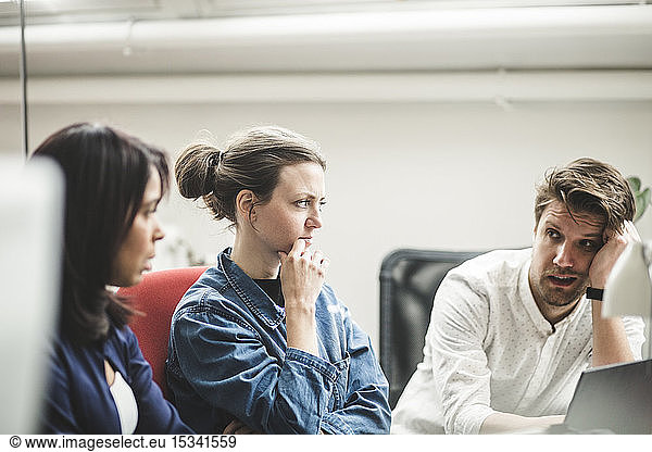 Businessman discussing with female professionals in meeting at creative office