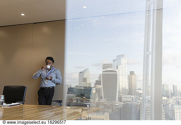 Businessman drinking coffee in highrise conference room  London  UK