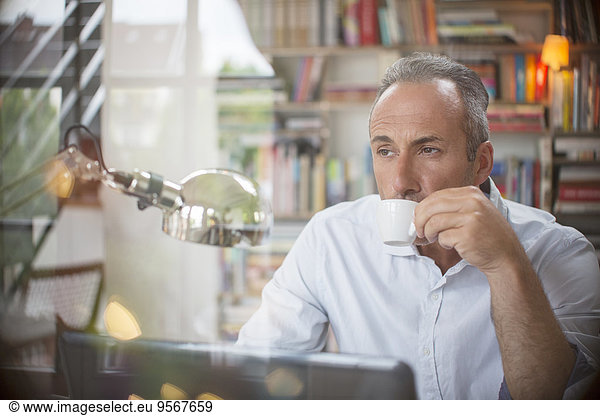 Businessman drinking cup of espresso in home office