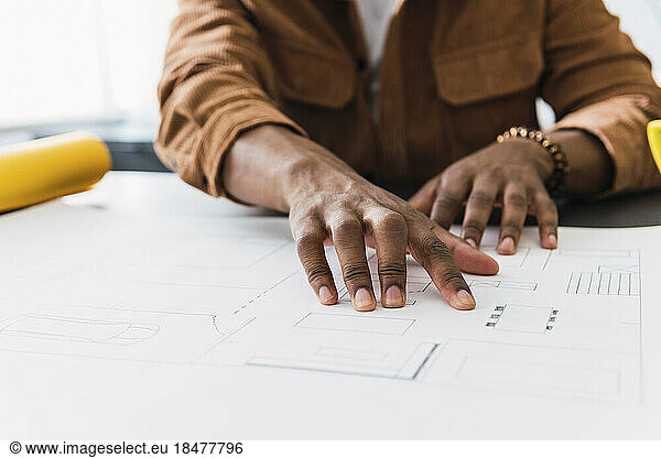 Businessman examining blueprint at desk in office