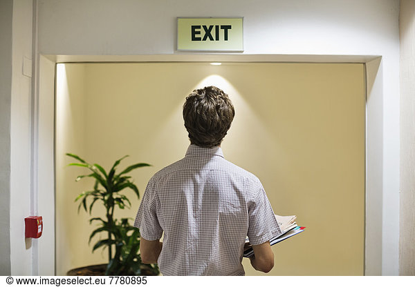 Businessman examining ‘exit’ sign in office