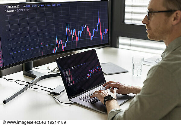 Businessman examining graph on desktop PC at desk