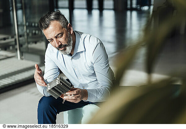 Businessman examining machine part in office