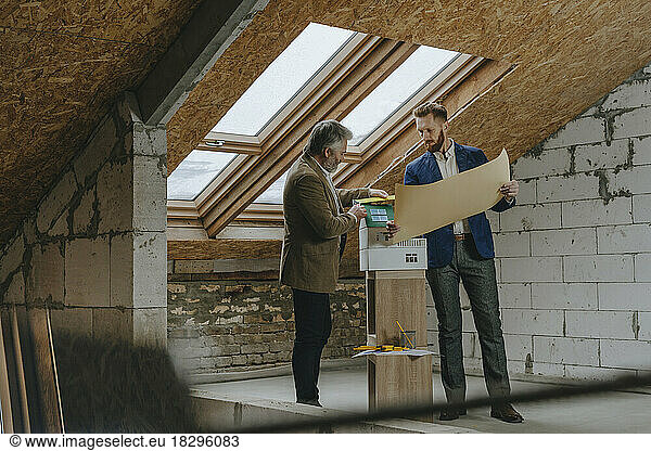 Businessman explaining blue print to colleague at construction site