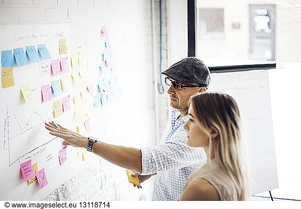 Businessman explaining strategy to female colleague at creative office