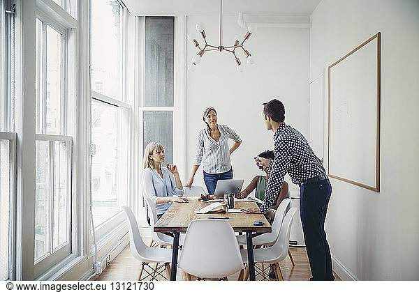 Businessman explaining strategy to female colleagues in board room