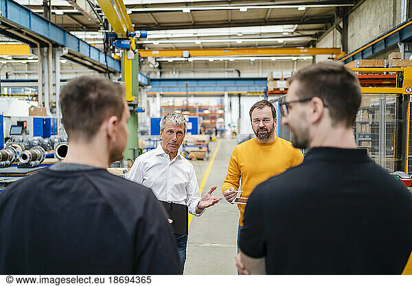 Businessman explaining to employees in meeting at factory