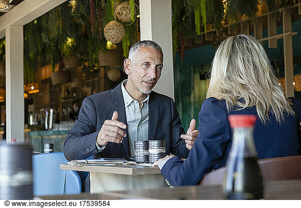 Businessman gesturing talking to client in restaurant