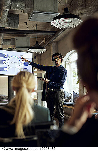 Businessman gesturing while explaining to colleague during meeting
