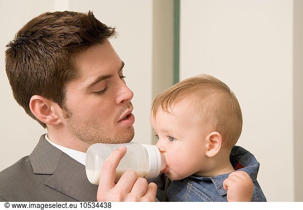 Businessman giving bottle to baby