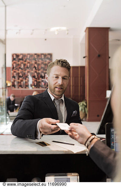 Businessman giving credit card to receptionist at hotel reception