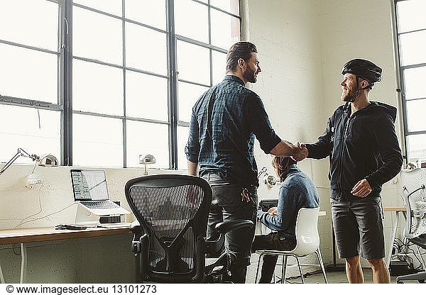 Businessman giving handshake to colleague in creative office