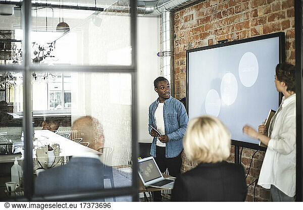 Businessman giving presentation to male and female investors in office