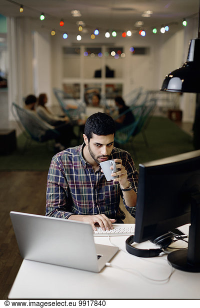 Businessman having coffee while working late in creative office