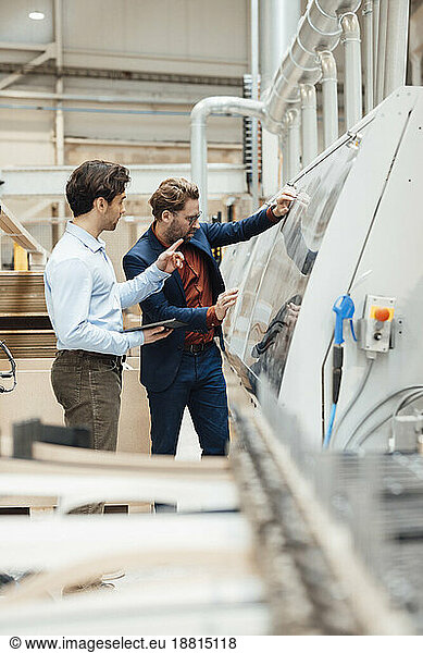 Businessman having discussion over machinery with colleague at industry