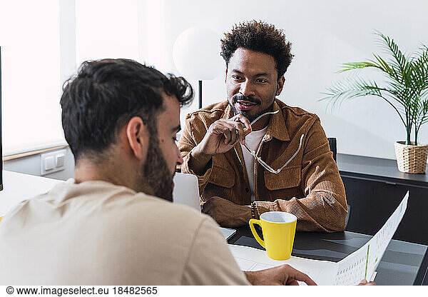 Businessman having discussion with colleague sitting at desk