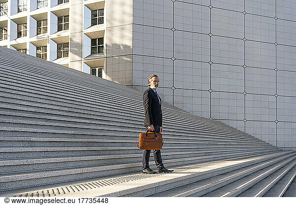 Businessman holding bag standing on staircase