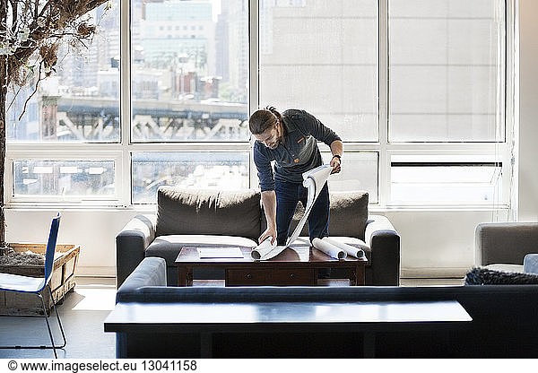 Businessman holding blueprint on table in creative office