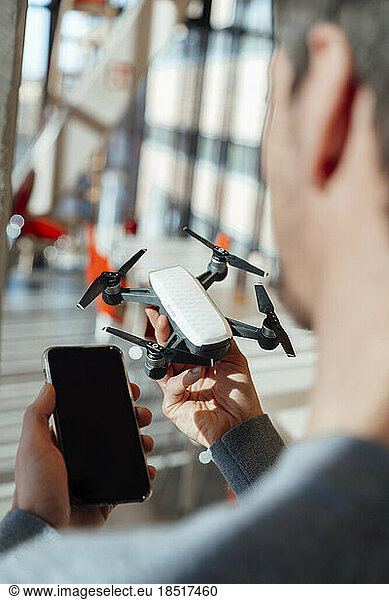 Businessman holding drone and smart phone in office
