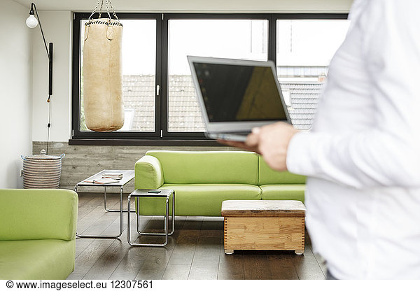 Businessman holding laptop  punch bag in the background