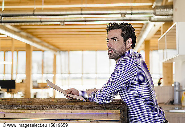 Businessman holding papers in wooden open-plan office