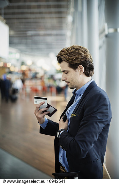 Businessman holding passport and credit card at airport