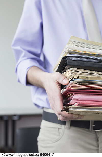 Businessman holding stack of files in office  close up