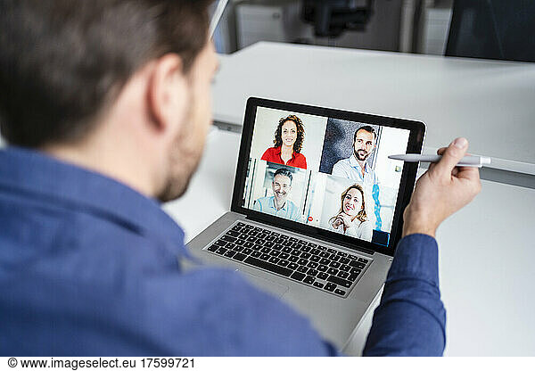 Businessman in discussion with colleagues on video call through laptop at office