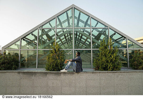 Businessman in front of glass house at sunset