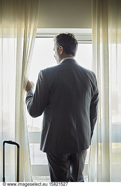 Businessman in hotel room looking out of window