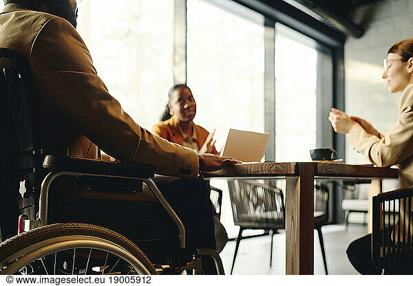 Businessman in wheelchair discussing with coworkers at conference table