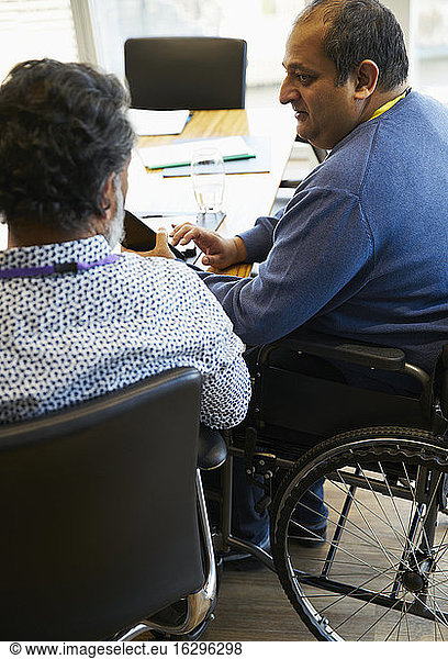 Businessman in wheelchair talking with colleague in meeting