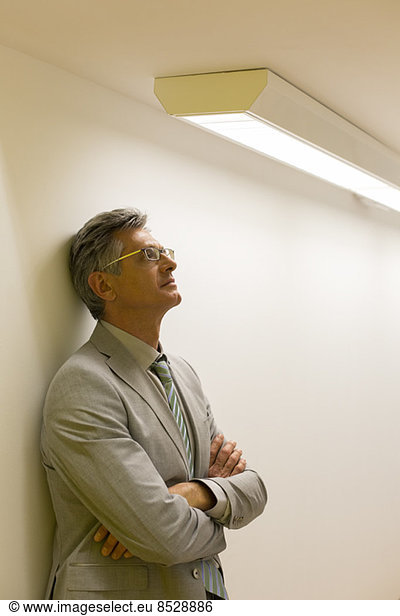 Businessman leaning against office wall