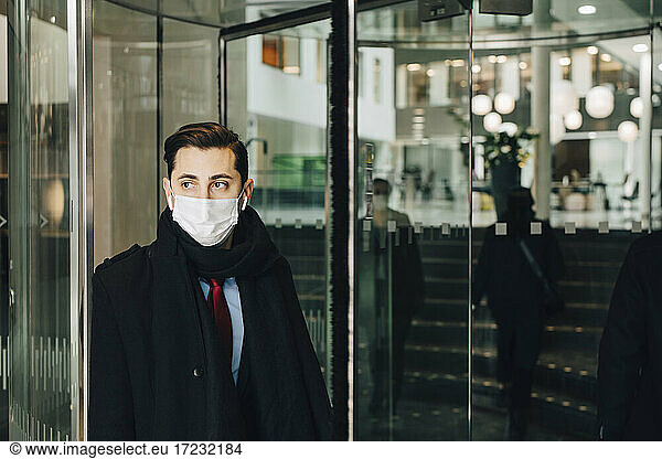 Businessman leaning on glass door in shopping mall during pandemic
