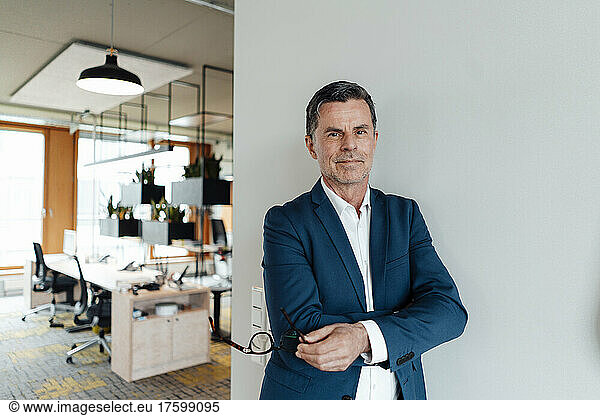 Businessman leaning on wall at office