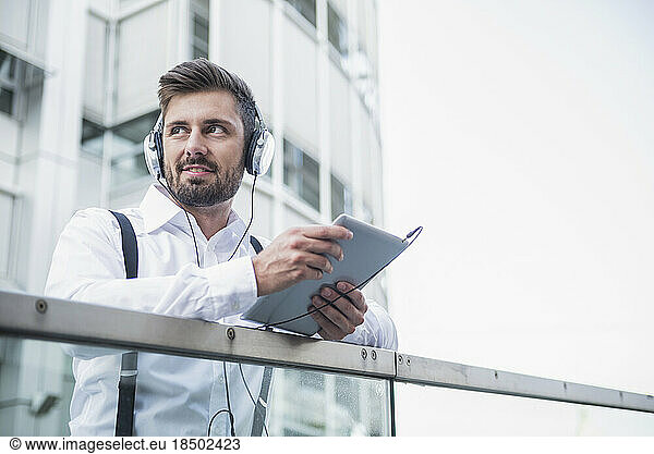 Businessman listening music with headphone in digital tablet  Munich  Bavaria  Germany